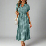 A woman wearing a green polka dot print button-up midi shirt dress with a natural waistline and short sleeves.
