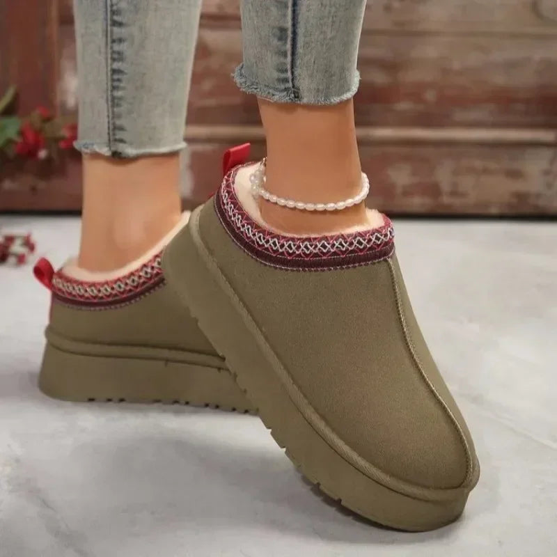 Beige slippers with red and white trim worn by a person on a light background