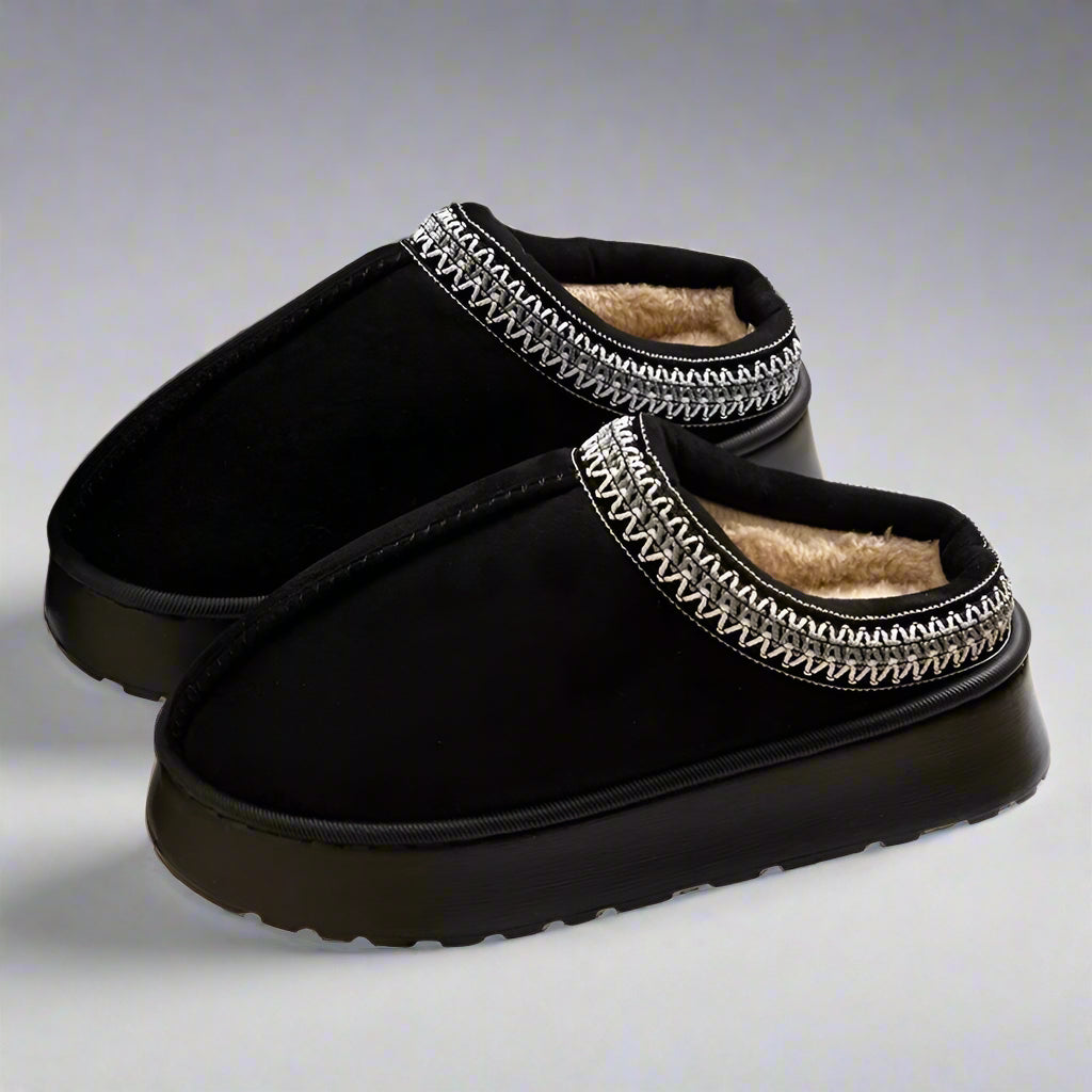Black slippers with decorative band on a white background