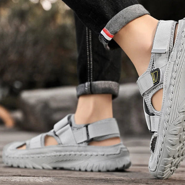 Gray sandals worn by a person on a wooden surface with a blurred background