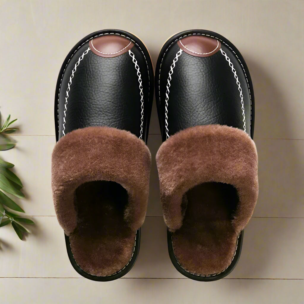 Pair of black slippers with brown fur on a white background