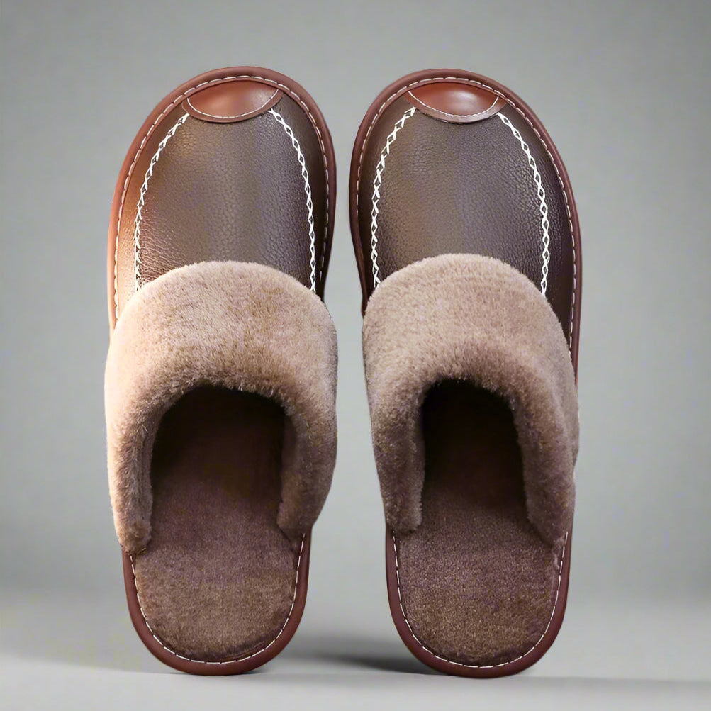 Pair of brown slippers with fuzzy lining on a textured surface