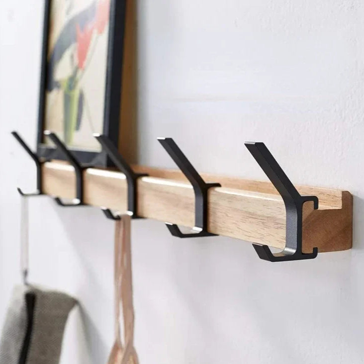 Wooden wall hook with black metal hooks on a white wall