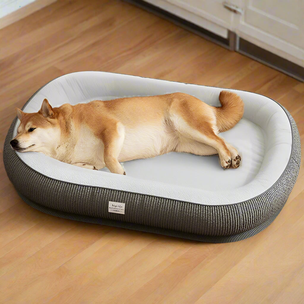 Dog lying on a gray pet bed with 'kevat vesi' branding on a wooden floor.