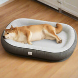 Dog lying on a gray pet bed with 'kevat vesi' branding on a wooden floor.