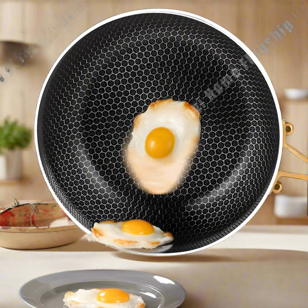 Black non-stick frying pan with fried eggs on a gray surface