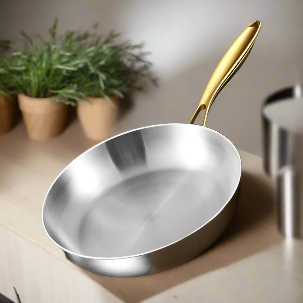 Stainless steel frying pan with gold handle on a dark background