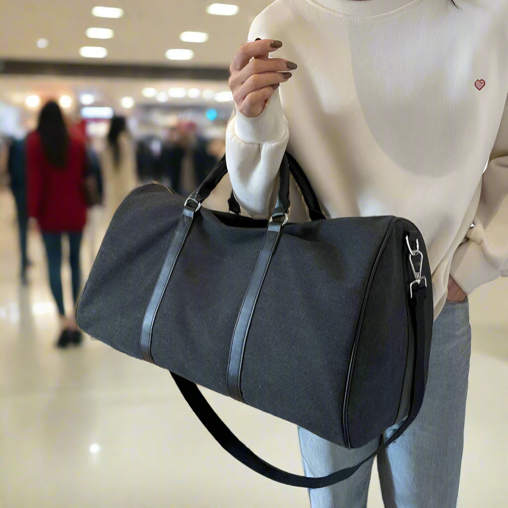 Person holding a gray duffel bag indoors