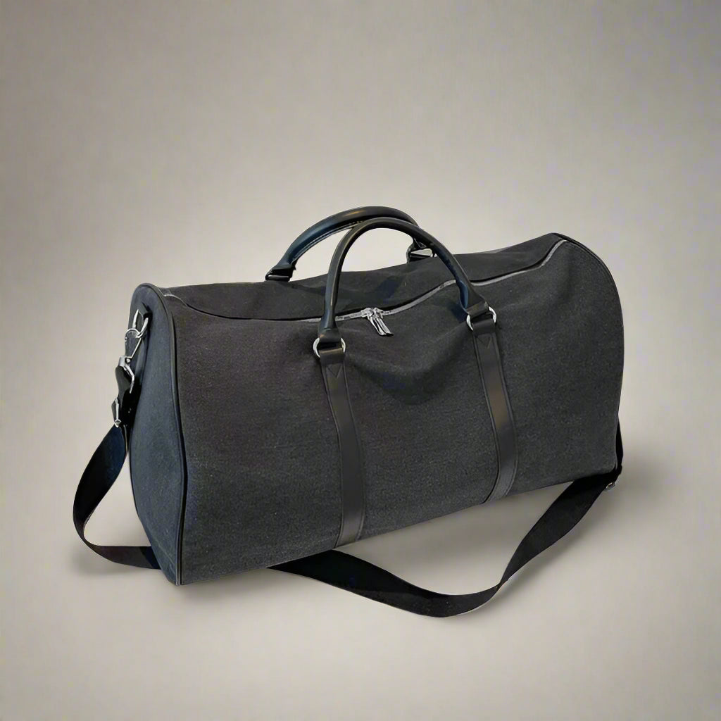 Gray duffel bag on a white surface with a blurred 'FOCUS' sign in the background