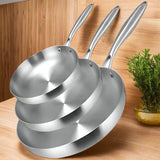 Set of three stainless steel frying pans stacked on a white background '' .