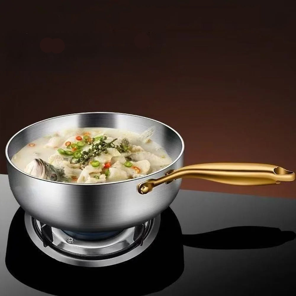 Stainless steel pot with gold handle containing a dish of food on a dark background