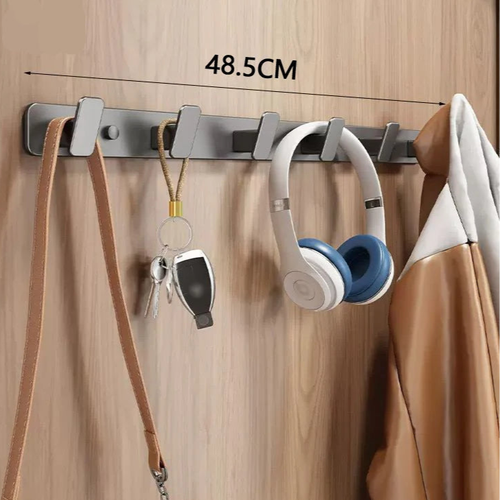 Wall-mounted hook with multiple hooks holding a strap, keys, and headphones on a wooden background.