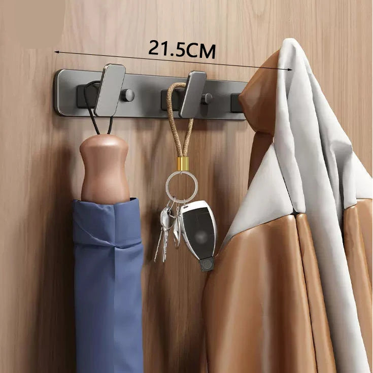 Wall-mounted hook with three hooks holding an umbrella, coat, and keys on a wooden surface.
