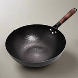 Black wok with a wooden handle on a white background