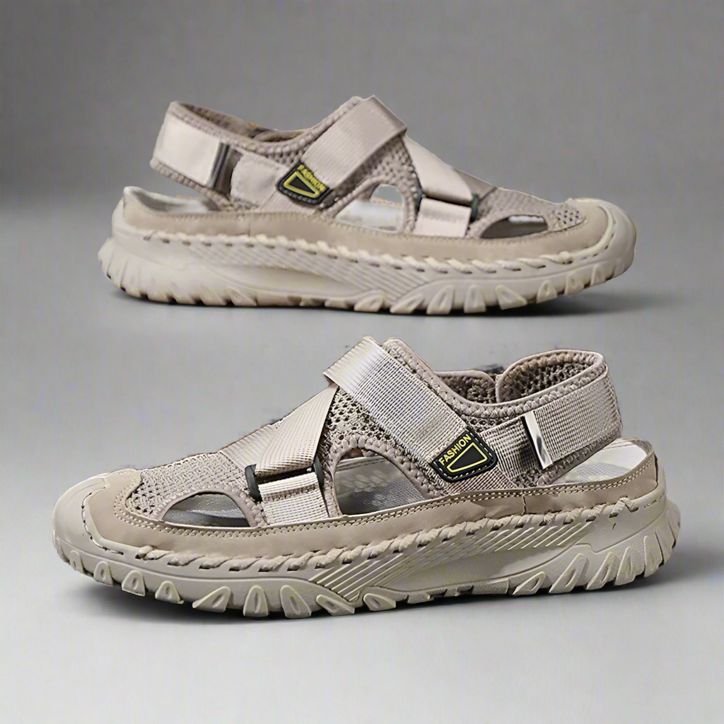 Pair of beige sandals on a reflective surface with a wooden block in the background