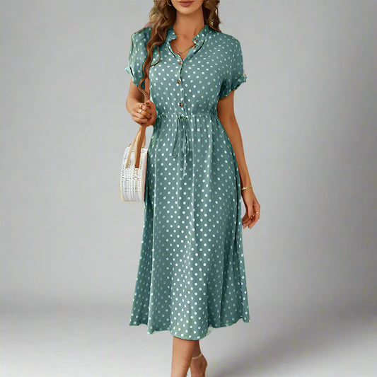 A woman wearing a green polka dot print button-up midi shirt dress with a natural waistline and short sleeves.
