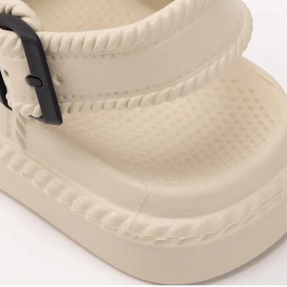 Beige sandal with a black buckle on a white background