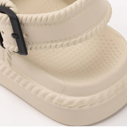Beige sandal with a black buckle on a white background