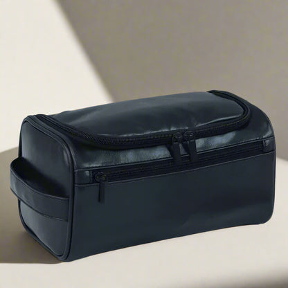 Black toiletry bag with dimensions displayed, placed on a light surface with grooming products.