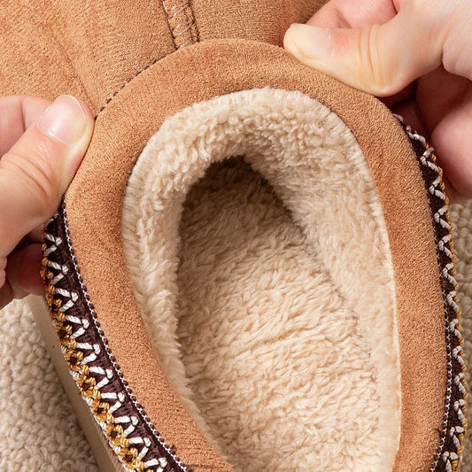 Close-up of a brown shoe with a fluffy white lining held by a hand.