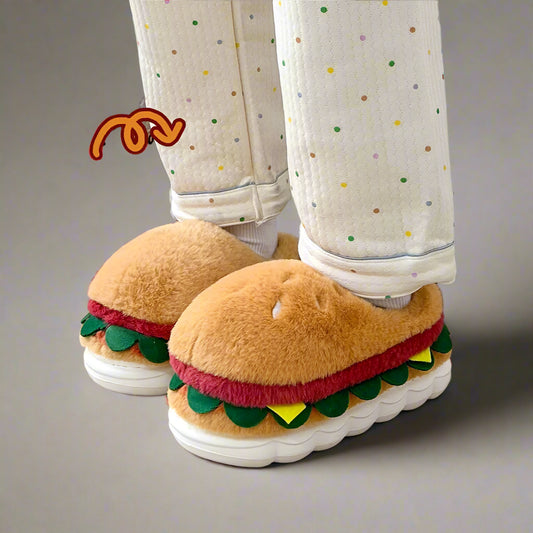 Hamburger-shaped slippers worn with light-colored pants on a wooden floor.