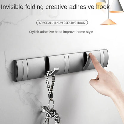 Invisible folding creative adhesive hook with a hand placing a keychain on it against a marble wall background.