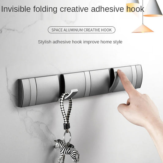 Invisible folding creative adhesive hook with a hand placing a keychain on it against a marble wall background.