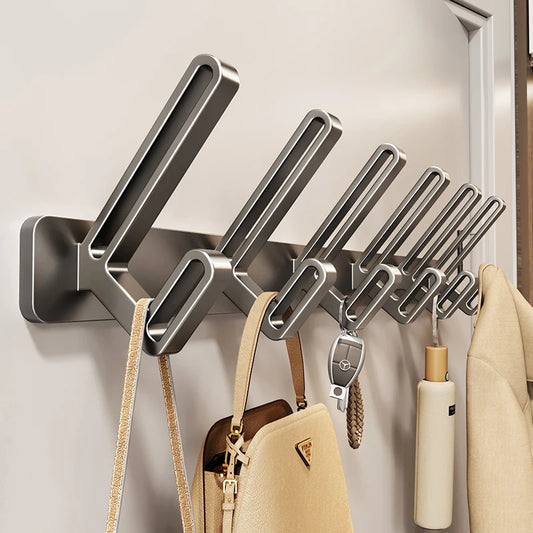 Metal wall-mounted hook rack with various items hanging on it against a neutral wall.