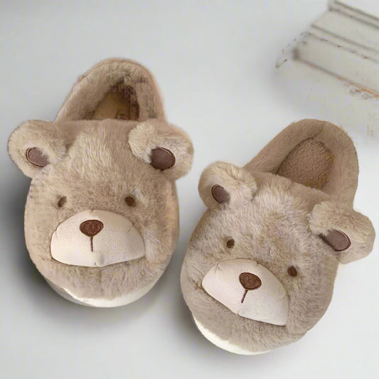 Pair of bear-shaped slippers on a surface with a wooden chair in the background.