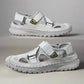 Pair of gray sandals with a visible brand logo on a reflective surface.
