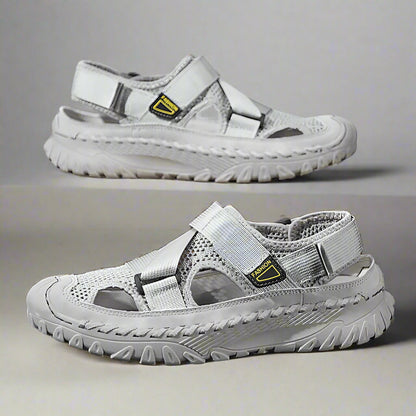 Pair of gray sandals with a visible brand logo on a reflective surface.