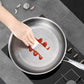 Person using a knife to spread red sauce on a non-stick frying pan on a stove.