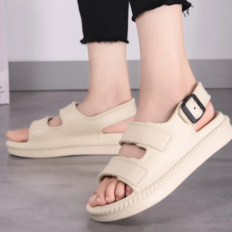 Beige sandals worn by a person on a neutral background
