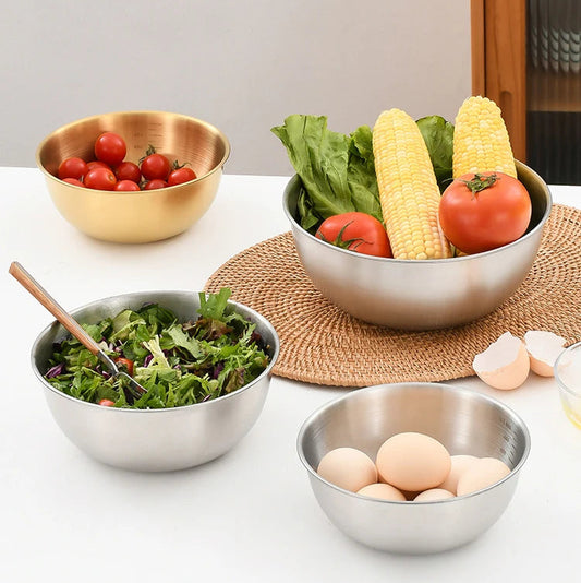 Stainless steel salad bowl with vegetables and eggs on a kitchen counter.
