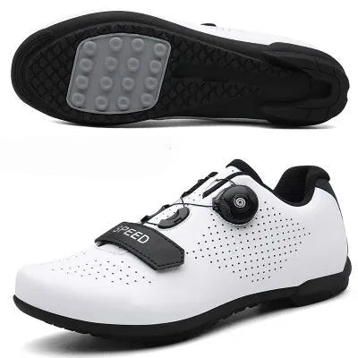 A person is adjusting the Velcro strap on a black cycling shoe with green accents, which is worn on a pedal of a bicycle.