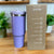 Purple tumbler with a cardboard box featuring product information on a reflective surface.