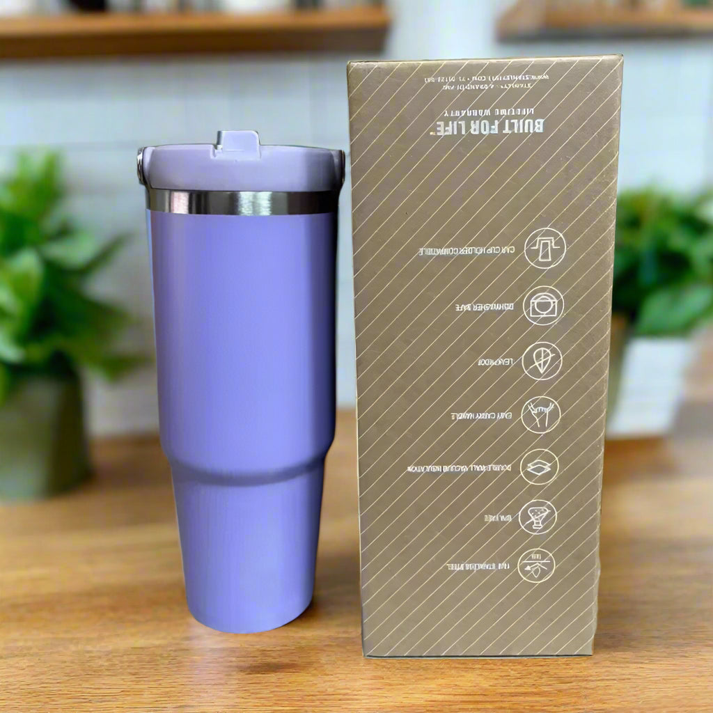 Purple tumbler with a cardboard box featuring product information on a reflective surface.