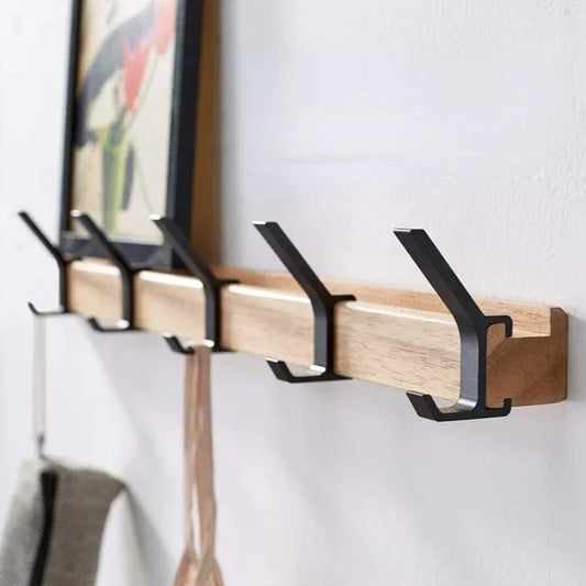 Wooden wall hook with black metal hooks on a white wall