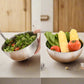 Two images showing a metal bowl with salad and another with vegetables and noodles.