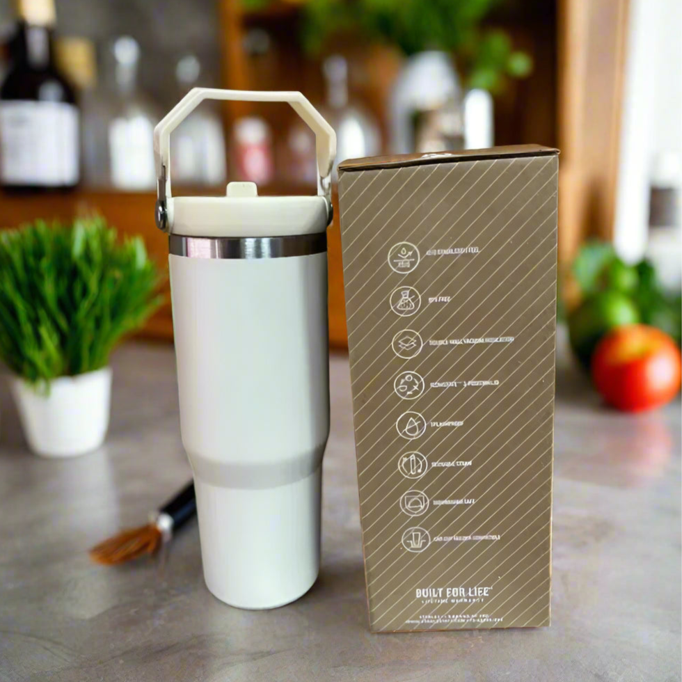 White tumbler with handle next to its packaging box on a cardboard background