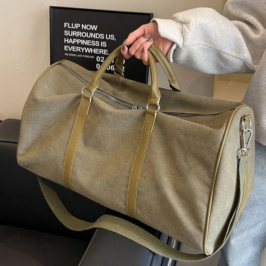 Person holding a beige duffel bag with a motivational poster in the background