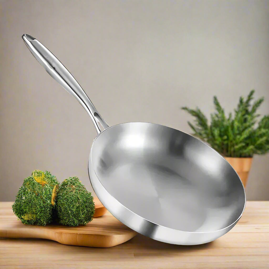 Stainless steel frying pan with food and vegetables on a white background, featuring the brand 'KEMORELA'.