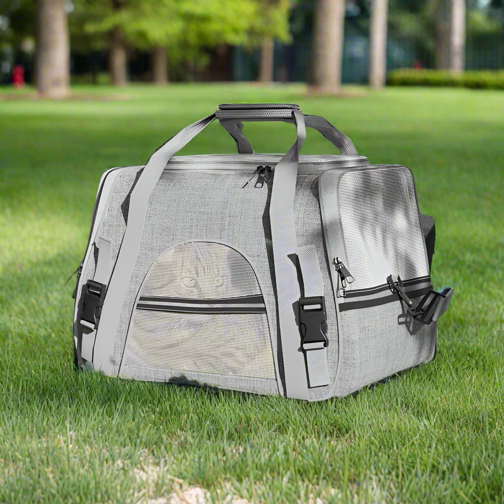 Gray pet carrier on grass with trees in the background