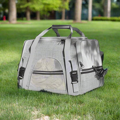 Gray pet carrier on grass with trees in the background