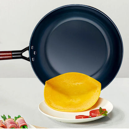 Blue frying pan with a yellow tortilla on a white plate against a light gray background