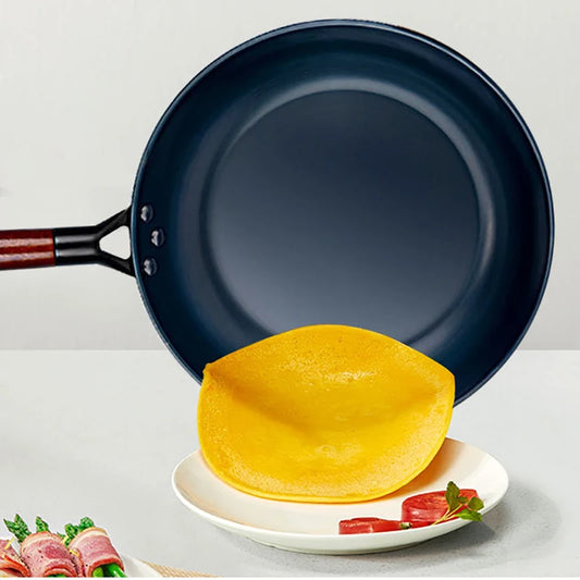 Blue frying pan with a yellow tortilla on a white plate against a light gray background