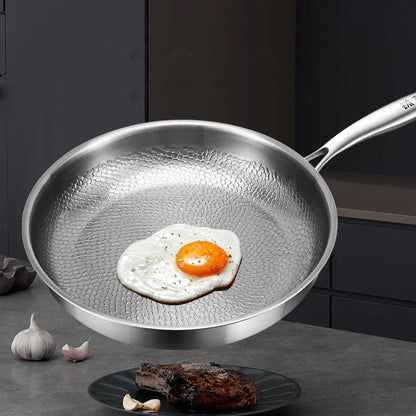 Stainless steel frying pan with a fried egg on a kitchen counter