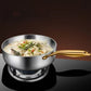 Stainless steel pot with gold handle containing a dish of food on a dark background
