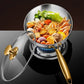Stainless steel pot with gold handle and lid on a stove, filled with noodles and vegetables.